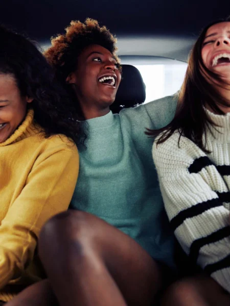 Friendly photo of a three women riding in the back of a clean taxi cab as passengers